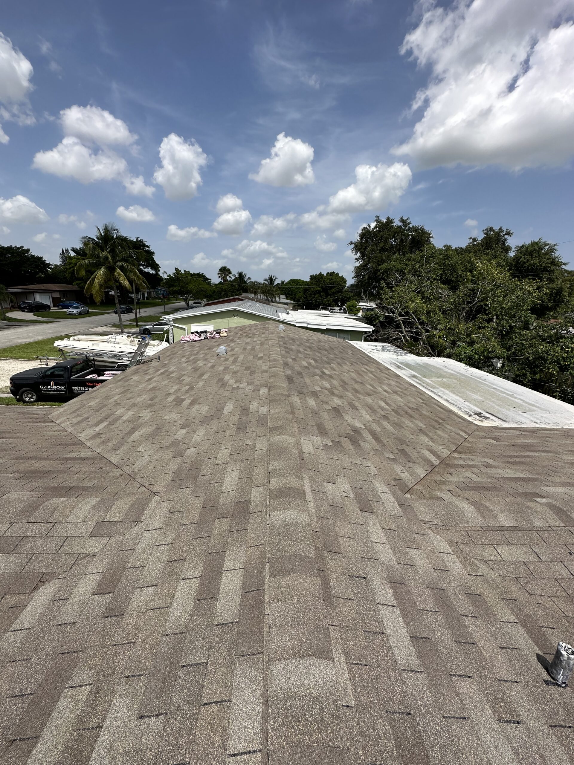 Roofer providing a free roof repair estimate in Coral Springs FL while inspecting shingles, flashing, and a roof leak area