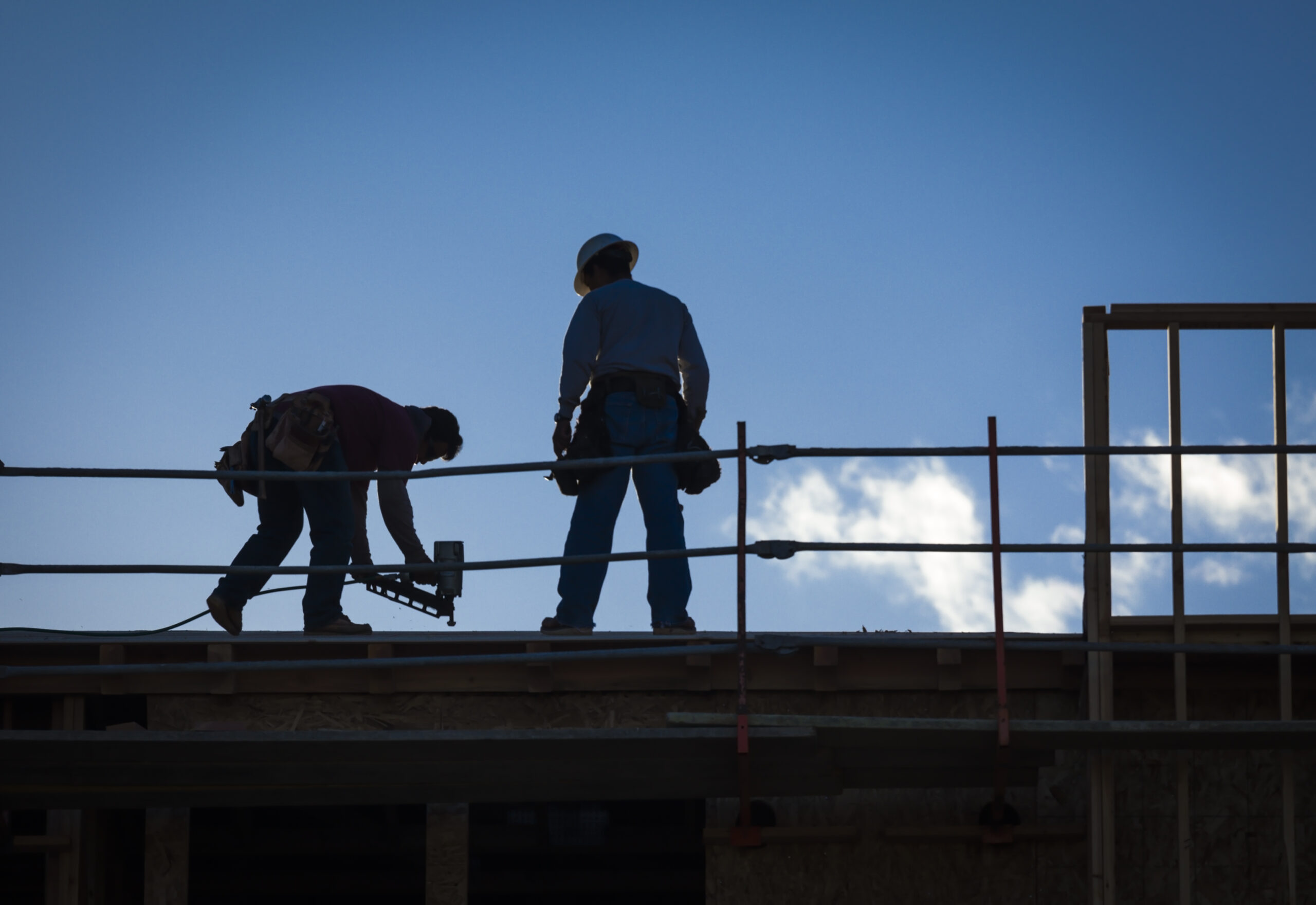 Two workers working on the roof of a building
